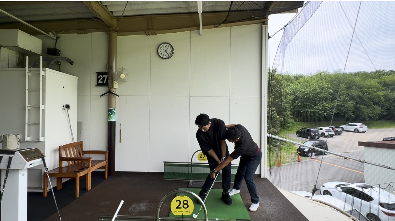 練習場でスイング中の動きをサポートする北川コーチの個別レッスン
